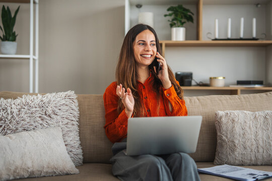 Young woman talking on phone working remotely from home - Powered by Adobe