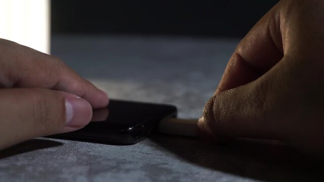 Hand unplugging USB charging cable from a smartphone, clean closeup showing device disconnection, daily routine, and power management concept.