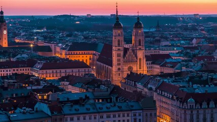 Aerial dusk view of a European city with tall churches, rooftops, and buildings under a colorful sky
