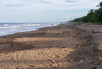 Sandy beach on the Atlantic coastline of Costa Rica at Tortuguero with tourists in background