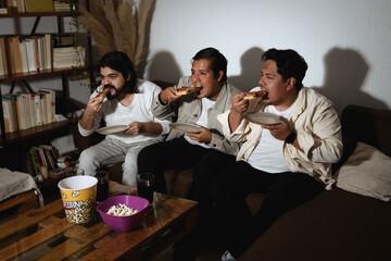 Three friends eating pizza during a relaxed home entertainment session