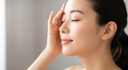 Young woman gently touching her forehead with eyes closed in peaceful moment