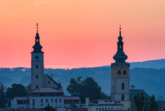 Aerial view of two majestic church towers piercing the rosy dawn sky, creating a silhouette against the distant hills, Banska Bystrica, Banska Bystrica Region, Slovakia.