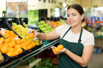 Woman seller in apron selects ripe mandarins in window to complete online order.Shopping online without leaving home,order collector