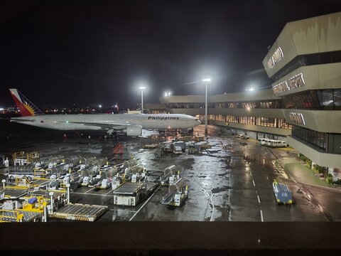 Night shot of a Philippine Airlines Boeing 777-300ER parked at a gate at Terminal 1 at Ninoy Aquino International Airport - Manila, Philippines