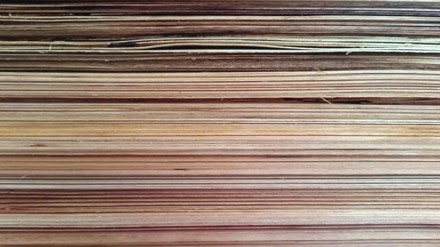Close up view of a stack of plywood, revealing the detailed layers of veneer and wood grain. A versatile texture for backgrounds and design projects.