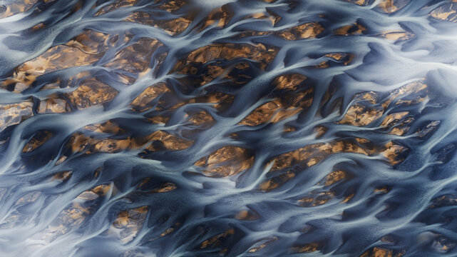 Aerial view of glacial rivers weaving through the rugged terrain, a tapestry of icy blues and earthy browns creating nature's abstract masterpiece, Hvolsvollur, Rangarbing eystra, Iceland.