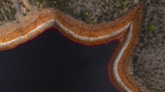 Aerial view of the winding, rust-colored banks contrasting with the dark water, creating a surreal landscape of intense hues and textures, R&iacute;otinto, Andalusia, Spain.