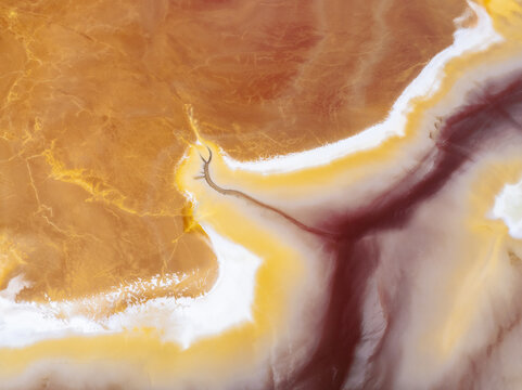 Aerial view of swirling, vibrant hues paint the landscape, where russet and ochre tones meet crimson streaks and creamy whites in a stunning display of color, Ríotinto, Andalusia, Spain.