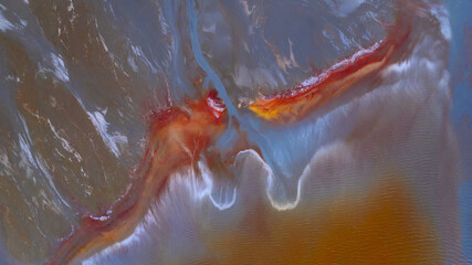 Aerial view of swirling, mineral-rich waters displaying vibrant hues of red, orange, and blue, creating an otherworldly landscape, Ríotinto, Andalusia, Spain.