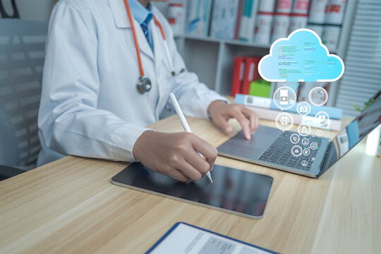 Doctor using stylus on digital tablet with laptop, cloud computing icons, medical data interface, modern healthcare technology workflow, innovation in e-health systems.