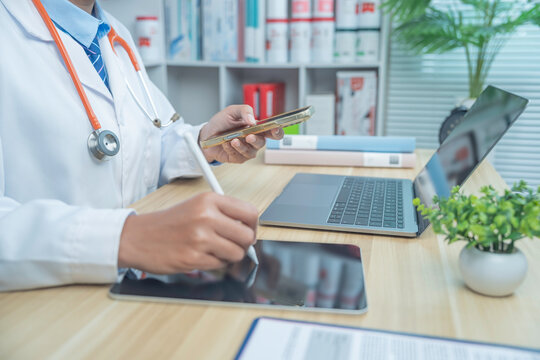 Doctor working on laptop with pen in hand in a clinical office. Modern healthcare workflow, digital record input, professional medical environment, and clean composition with clear text space.
