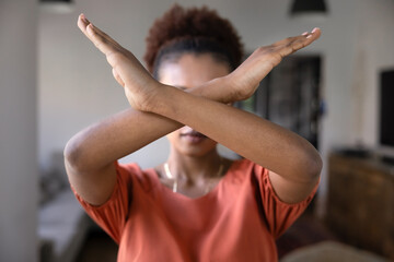 Serious young African woman showing arms crossed in ban gesture