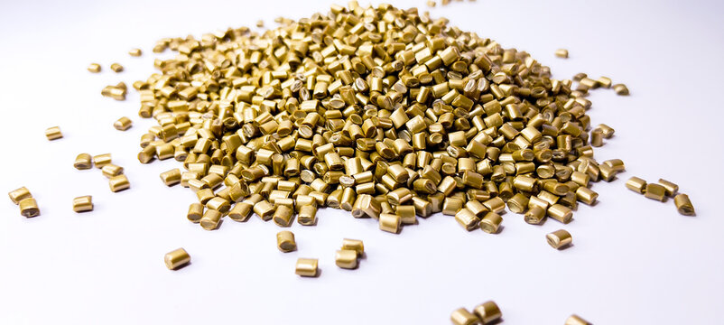 plastic masterbatch, gold masterbatch granules as virgin polymer resin pigment, poured into white background media, suitable for industrial plastic company profile product catalog design, top view