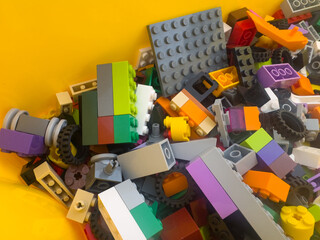 Fototapeta premium BELO HORIZONTE, MG, BRAZIL – NOVEMBER, 22, 2025: A pile of colorful LEGO building blocks and parts on a yellow background.