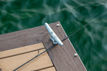 Fishing rod resting on a dock during a calm day on the water, with gentle waves creating a serene backdrop
