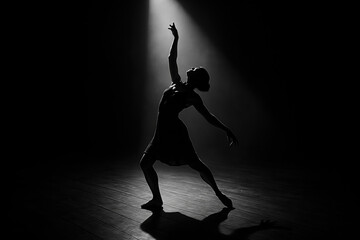Ballet dancer in silhouette under a spotlight on a dark stage