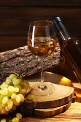 Delicious white wine in glass, bottle and grapes on wooden table