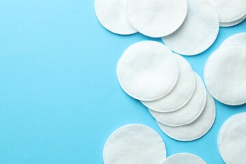 Obraz premium Clean cotton pads on light blue background, flat lay. Space for text