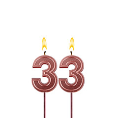 Candle number 33 - Lit birthday candle on white background