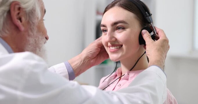 Hearing test. Doctor adjusting patient's audiometric headphones in clinic. Camera moving left