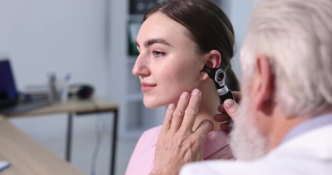 Hearing test. Doctor examining patient&rsquo;s ear with otoscope in clinic
