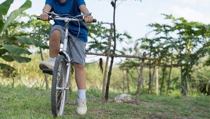 Girl riding a bicycle outdoors in a green natural area.