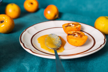 Tejocotes jam and halved fruits on plate with spoon
