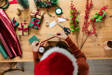 Holiday gift boxes are resting on table and red and green paper rolls are lying nearby