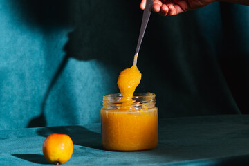 Hand scooping sweet homemade apple jam from jar