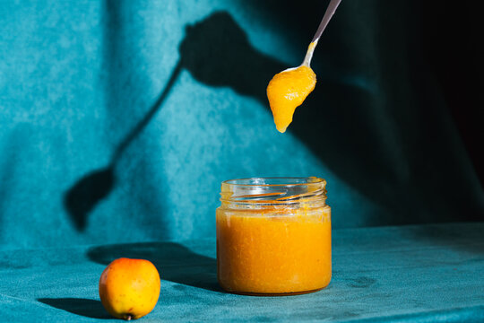 Spoon dripping homemade tejocote jam into glass jar