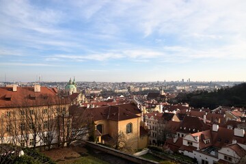 Fototapeta premium Scenic high-angle view of the medieval Old Town of Tallinn, Estonia, showcasing red tiled roofs, church spires, and historic architecture under a blue sky with clouds.