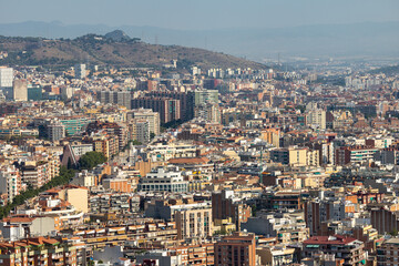 Obraz premium Urban panorama of Barcelona from Glories Tower on clear summer day, showing dense expanse of residential blocks and compact structure of city in soft daytime light