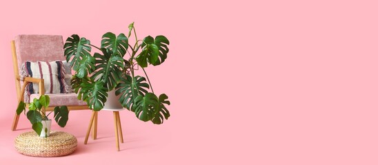 Table with houseplants, armchair and pouf on pink background with space for text