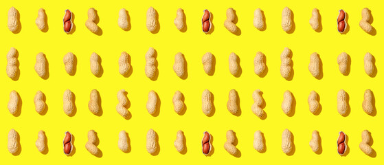 Many unpeeled peanuts on yellow background
