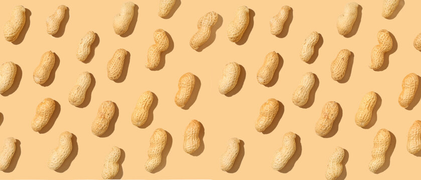 Many unpeeled peanuts on beige background