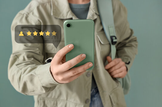 Young woman with mobile phone giving feedback on green background, closeup