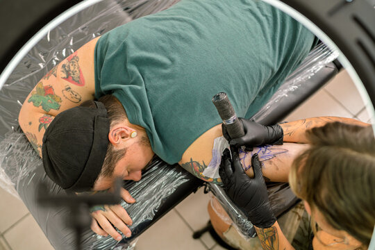 Tattoo artist tattooing new design on client's arm