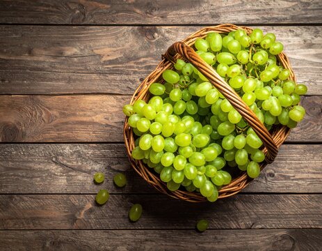 A pile of fresh grapes in a basket on a wooden table. top view.