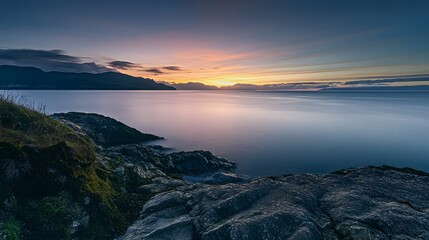Rocky coastline at sunrise over calm ocean water image