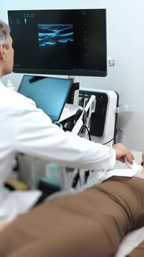 Doctor performing an ultrasound examination with a handheld probe on a patient using modern diagnostic equipment in a clinical environment, captured indoors in a medical setting.