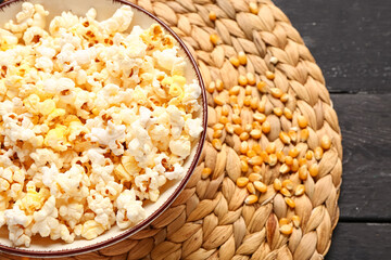 Bowl with tasty popcorn on black wooden background