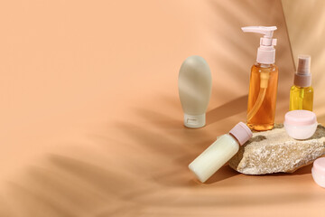 Stone with set of travel cosmetic products on color background
