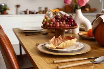 Autumn table setting with pumpkins, grapes and dry leaves
