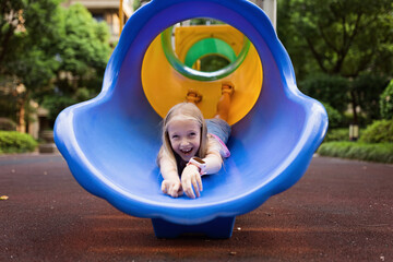 Cute schoolgirl walking outdoor on playground at summer. Lonely during covid-19 quarantine. Child can't play with friends while coronavirus pandemic.