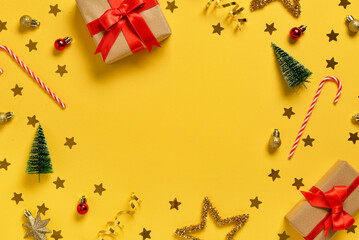 Frame made of gift boxes with Christmas decorations and candy canes on yellow background