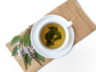 Cat's whiskers leaf tea (Orthosiphon aristatus) in a cup with fresh leaf and flower. Herbal drink for health, Flat lay 
