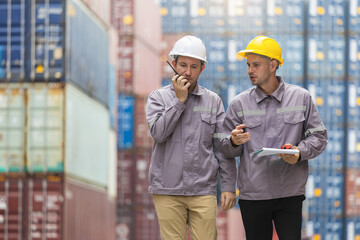 Logistics industrial workers communicating and inspecting cargo containers at port, Engineers discussing freight operations while using walkie talkie at shipping yard