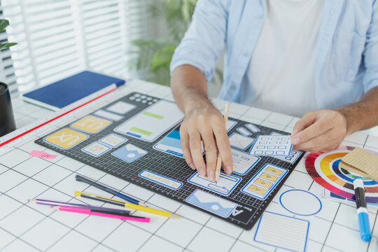 A male designer focused on UX UI tasks, creating app prototypes with wireframes, sketches, and color palettes. He works with creative ideas to optimize user interface and usability.