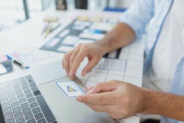 A male designer focused on UX UI tasks, creating app prototypes with wireframes, sketches, and color palettes. He works with creative ideas to optimize user interface and usability.